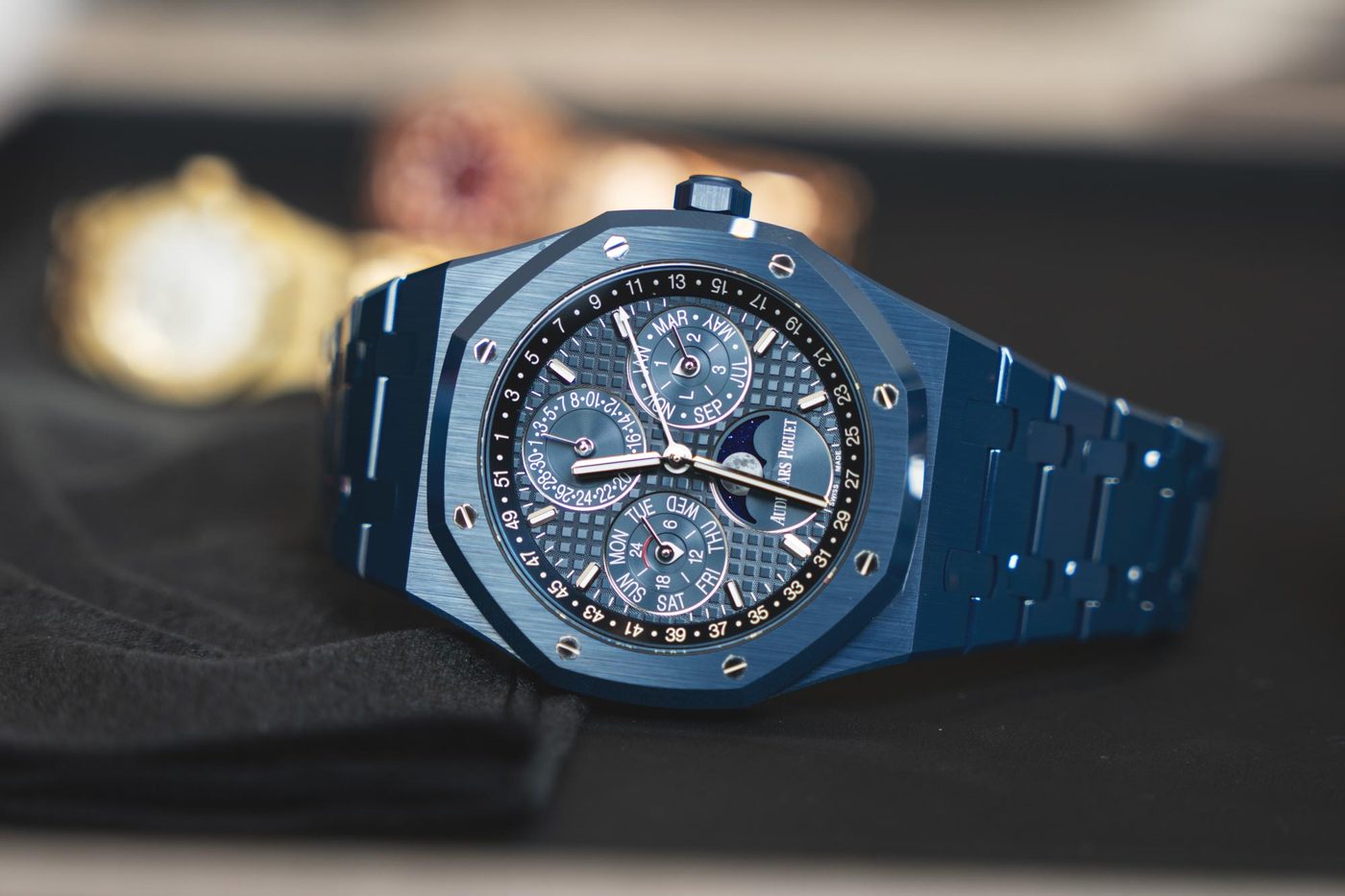 Blue ceramic Audemars Piguet Royal Oak perpetual calendar watch with moon phase, resting on dark cloth