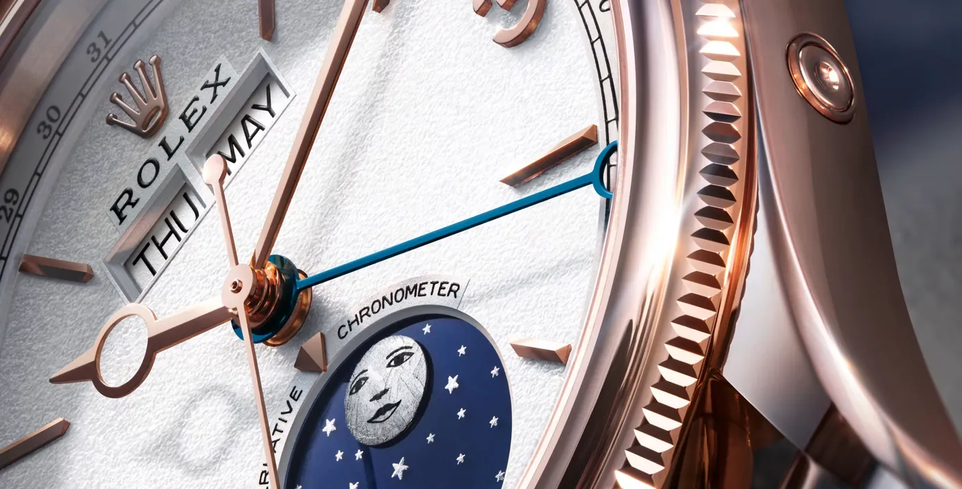 Close-up of the white dial of a rose gold luxury watch, with hands, date and moon phase